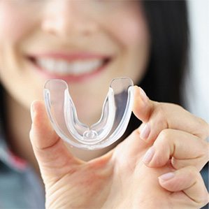 A smiling woman holding a transparent mouthguard