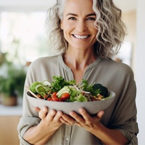 a woman smiling while holding a bowl of healthy food