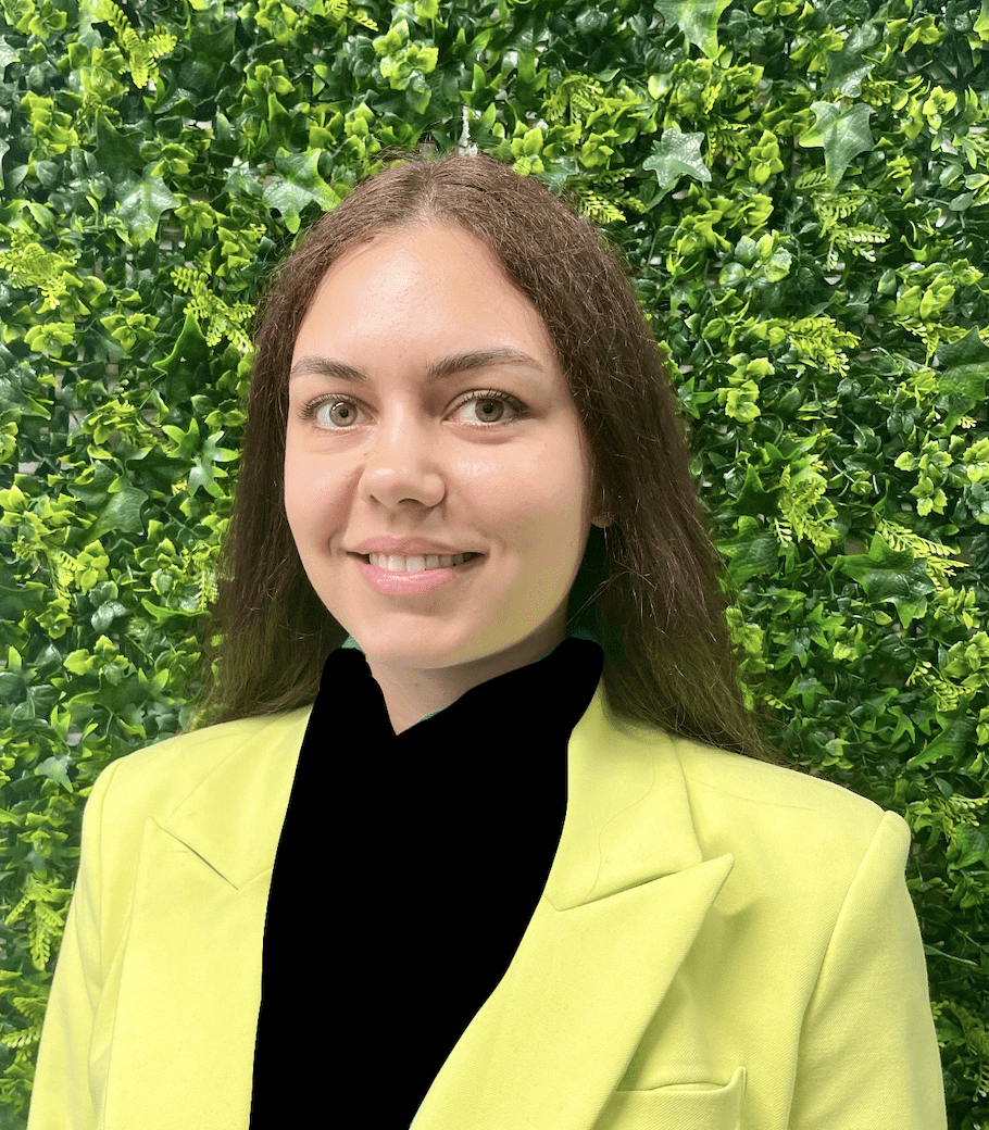 A woman in a yellow jacket standing next to a green wall.