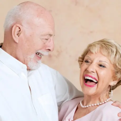 A man and woman laughing together while standing next to each other.