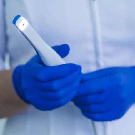 A person wearing blue gloves holding a white phone.