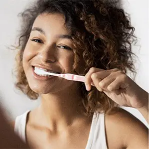 A woman is brushing her teeth with an electric toothbrush.