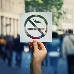 A person holding up a no smoking sign