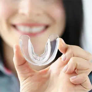 A woman holding an orthodontic appliance in her hand.