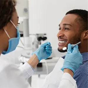 A man is getting his teeth checked by an dentist.