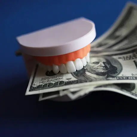 A tooth brush and money on top of blue background.