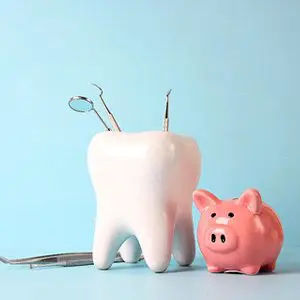 A tooth with dental tools next to it and a piggy bank.