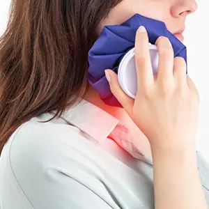 A woman holding her neck in pain while talking on the phone.