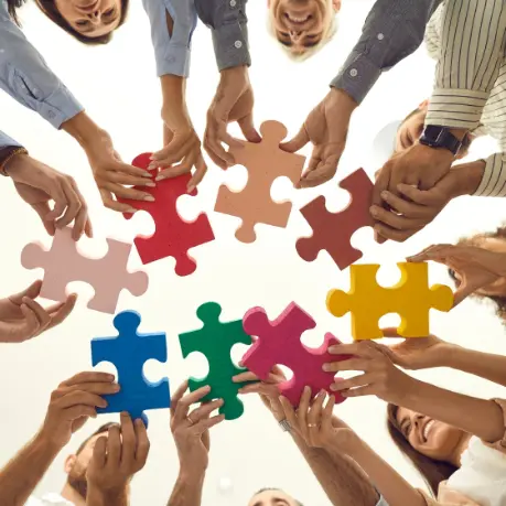 A group of people holding up puzzle pieces.