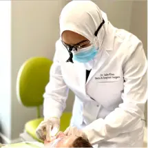 A dentist is wearing white and has a mask on.