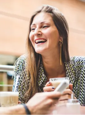 A woman smiling while holding her phone.