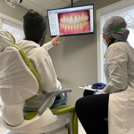 A dentist showing a patient how to brush his teeth.