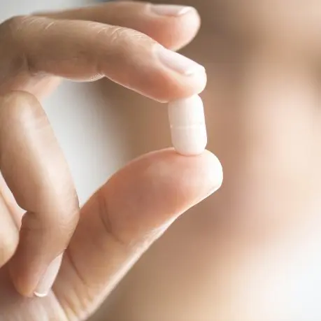 A person holding an empty pill bottle in their hand.