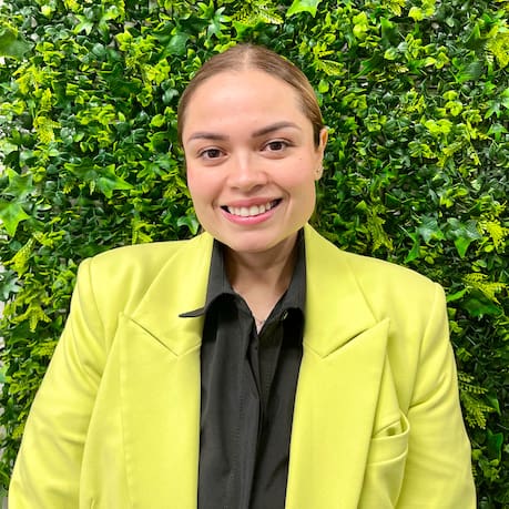 A woman in a yellow jacket standing next to a green wall.